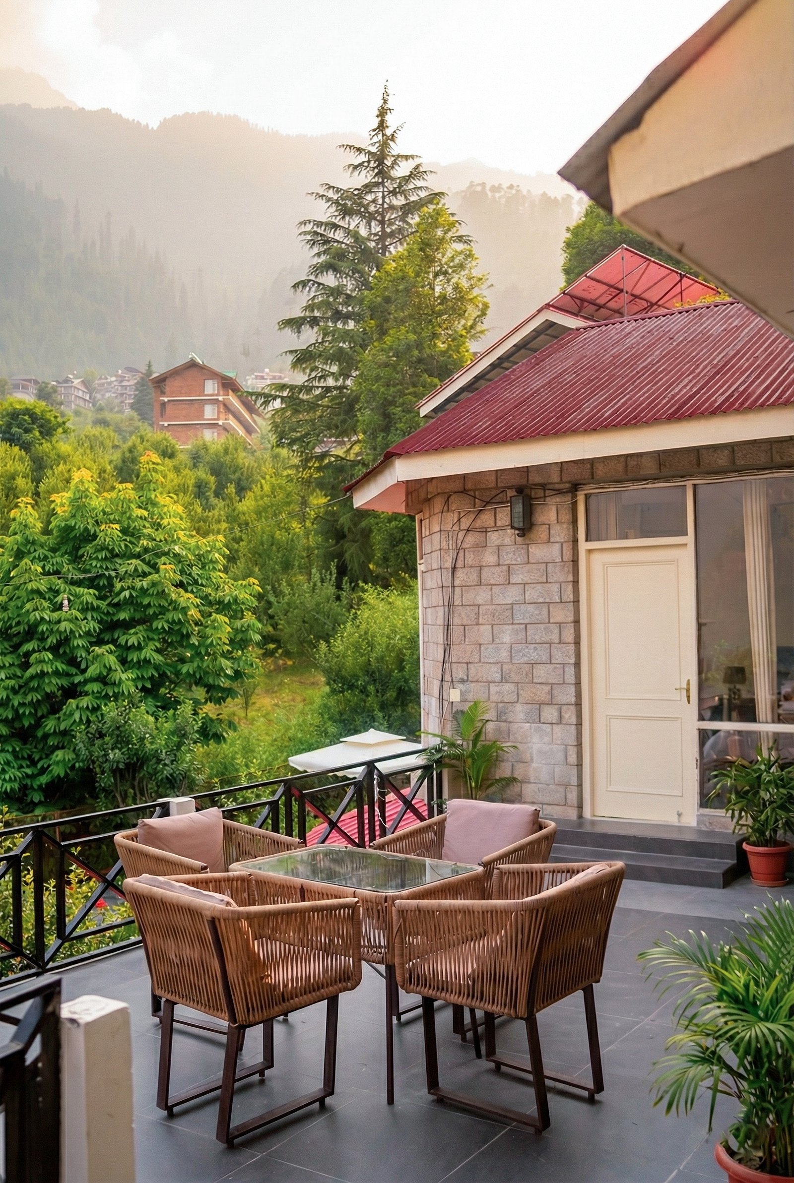 Cozy balcony seating area with cushions at Forestbound Cottage overlooking dense forest and mountain trails in Manali